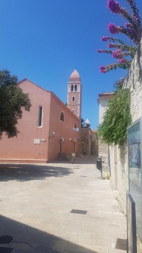 a large red building with a clock tower at Apartment Lavanda garden in Rab