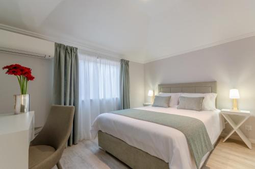 a bedroom with a large white bed and a chair at Ver Belém Suites in Lisbon