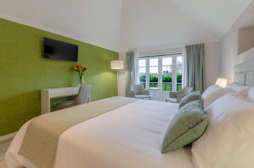 a bedroom with a large white bed with green walls at Ver Belém Suites in Lisbon