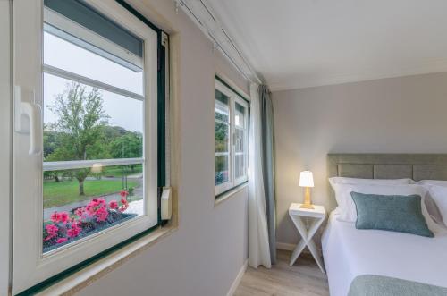a bedroom with a window with a bed and flowers at Ver Belém Suites in Lisbon