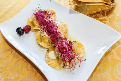 a white plate topped with fruit and purple seaweed at Hotel Al Lago in Soraga