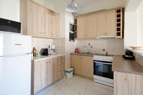 uma cozinha com armários de madeira e um frigorífico branco em Athens Heartbeat em Atenas