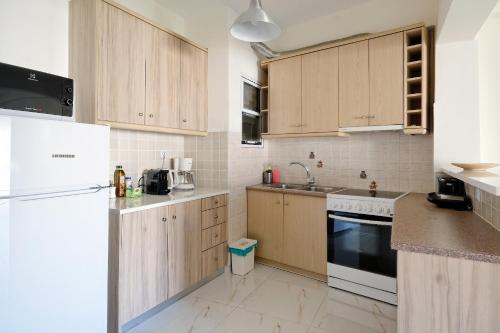kuchnia z drewnianymi szafkami i białą lodówką w obiekcie Athens Heartbeat w Atenach