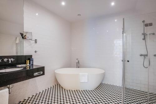 a white bathroom with a tub and a shower at Eurostars Danube Budapest in Budapest