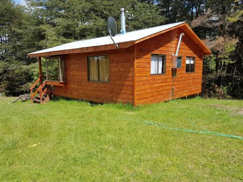 a small wooden cabin in a field of grass at Cabaña Mirador Caburgua in Caburgua