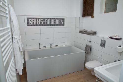 a white bathroom with a tub and a toilet at The Originals Hôtel Le Cise Restaurant Chambres et Suites in Ault