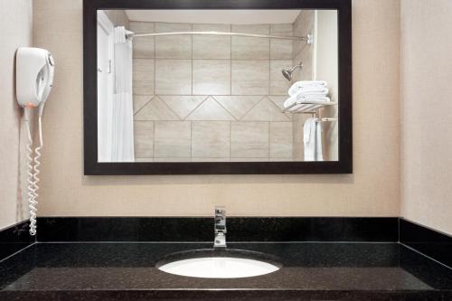 a bathroom sink with a phone and a mirror at Days Inn by Wyndham Sylvan Lake in Sylvan Lake