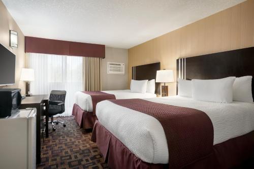 a hotel room with two beds and a television at Days Inn by Wyndham Sylvan Lake in Sylvan Lake