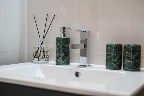 eine Badezimmertheke mit drei grünen Vasen und einem Waschbecken in der Unterkunft Lx Design Apartment near Congress Center in Lissabon
