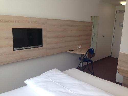 a room with two beds and a tv on a wall at Autohof Bitterfeld in Bitterfeld