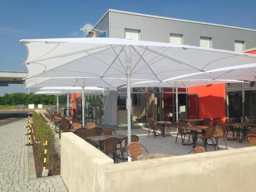 a patio with tables and chairs under a white umbrella at Autohof Bitterfeld in Bitterfeld