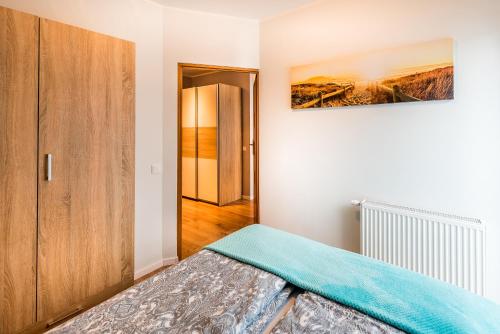 a bedroom with a bed with a blue blanket on it at Apartament B&F Garbary Poznań Business & Family - Parking in Poznań