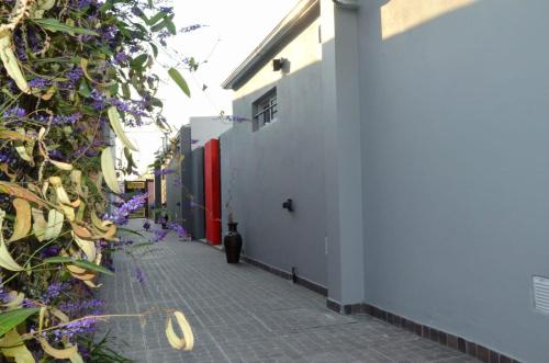 un callejón con flores púrpuras junto a un edificio blanco en Departamentos Victorino en Ramallo