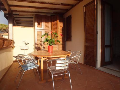 un tavolo in legno con sedie su un balcone con piante di Appartamento Il Sole a Marina di Campo