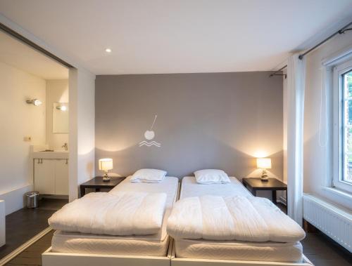 2 Betten in einem Zimmer mit 2 Tischen und einem Fenster in der Unterkunft De Waterkriek in Borgloon
