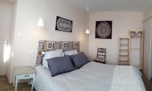 une chambre avec un grand lit blanc et une chaise dans l'établissement La chenevière, à Saint-Rémy-de-Chargnat