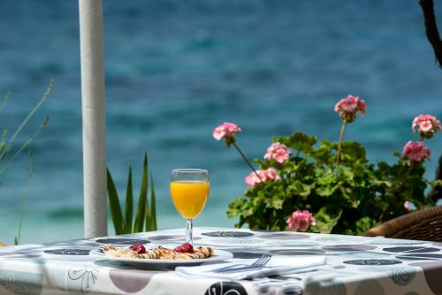 a table with a glass of orange juice and a plate of food at Beach House Poseydon in Mlini
