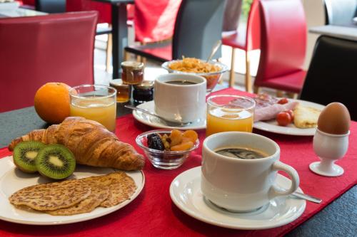 a table topped with plates of breakfast foods and coffee at Hôtel Tour Maje in Rodez