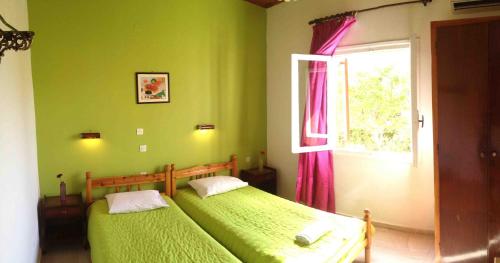 two beds in a green bedroom with a window at Ionian Breeze Apartments in Kavos