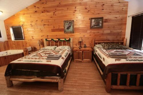 two beds in a room with wooden walls at Dancing Bear in Sevierville