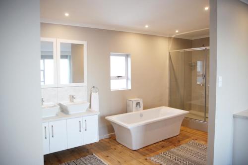 a white bathroom with two sinks and a shower at Eden Guesthouse B&B in Dana Bay