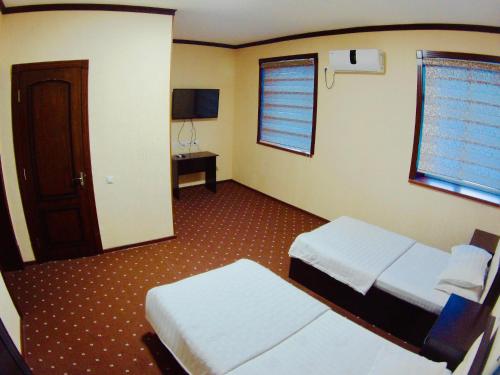ShahrisabzにあるBek Shahrisabzのベッド2台とテレビが備わるホテルルームです。