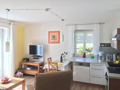 cocina con armarios blancos y mesa con TV en Ferienwohnung Kalin en Neualbenreuth