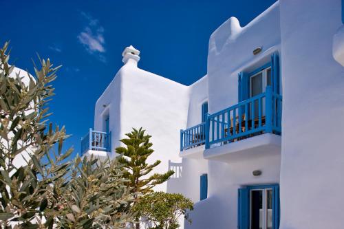 a white building with blue windows and a tree at Harmony Boutique Hotel in Mýkonos City