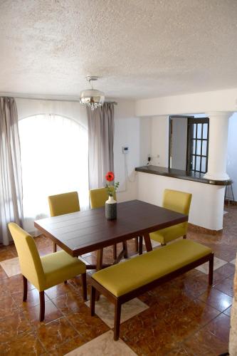 a dining room with a wooden table and yellow chairs at The House of Cinema in Guanajuato