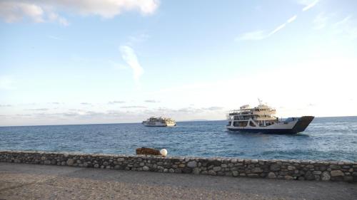 two boats in the water next to a stone wall at Zorbas Studios in Agia Roumeli