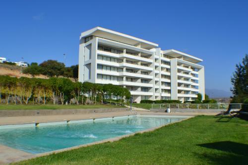 a large apartment building with a swimming pool in front of a building at Apartamento Puerto Velero Tongoy in Puerto Velero