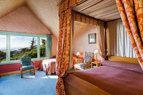 um quarto com uma cama e uma grande janela em Larnach Lodge & Stable Stay em Dunedin