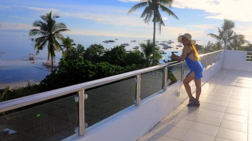 a woman standing on a balcony looking at the ocean at Bohol South Beach Hotel in Panglao