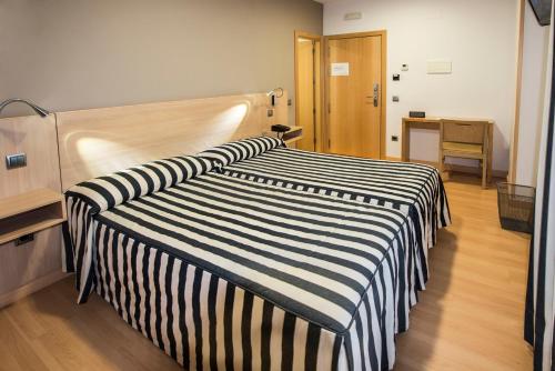 a hotel room with two beds and a desk at Hotel Puerta de la Santa in Ávila