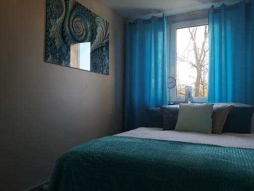 a bedroom with a bed with blue curtains and a window at Park Apartment 216 in Strzelce Opolskie