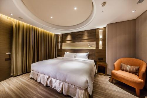 a bedroom with a large bed and a chair at Green World Taipei Station in Taipei