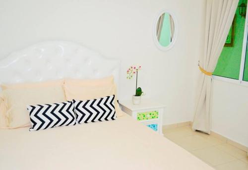 1 dormitorio blanco con 1 cama con 2 almohadas blancas y negras en CASA ADELIA HOMESTAY KEMAMAN, en Cukai