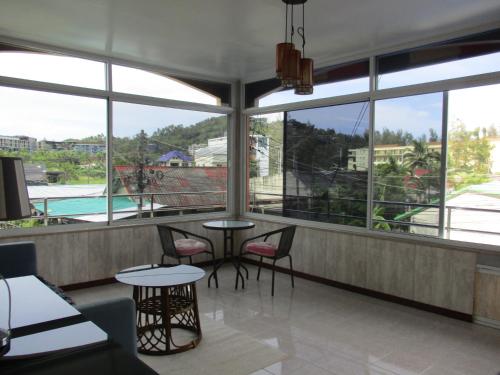 a restaurant with tables and chairs in a room with windows at Similan Hotel in Bang Tao Beach