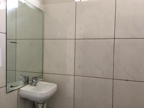 een witte badkamer met een wastafel en een spiegel bij Shingo's Backpackers in Adelaide