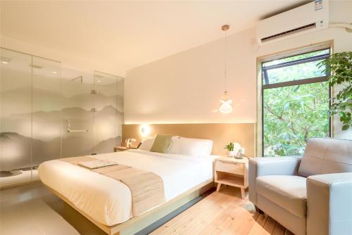a bedroom with a bed and a chair and a window at Zen Tea House Elephant Trunk Hill Park船舍茶椐象山店 in Guilin