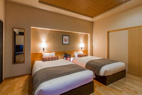 a hotel room with two beds and a tv at Migiwatei Ochi Kochi in Fukuyama