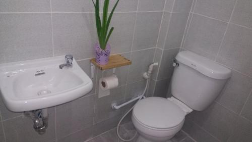 a bathroom with a toilet and a sink and a plant at Airport Travelodge Manila in Manila
