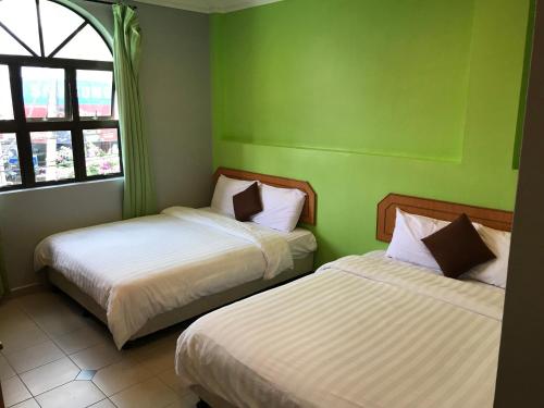 two beds in a room with green walls at Kangsar Hotel in Kuala Kangsar