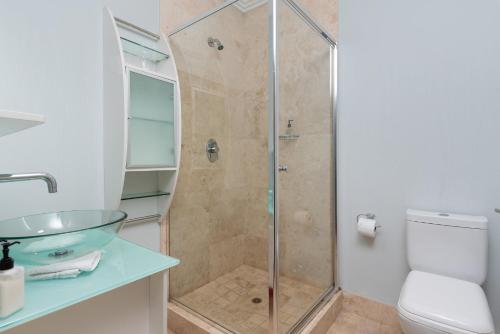 a bathroom with a shower with a toilet and a sink at 61 on Camps Bay in Cape Town