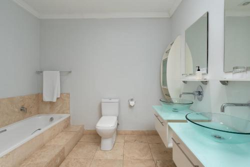 a bathroom with a tub and a toilet and a sink at 61 on Camps Bay in Cape Town