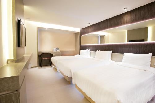 a hotel room with three beds and a television at Inhouse Hotel Yehliu in Wanli