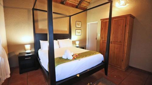 a bedroom with a four poster bed with flowers on it at African Rest Lodge in Barberton