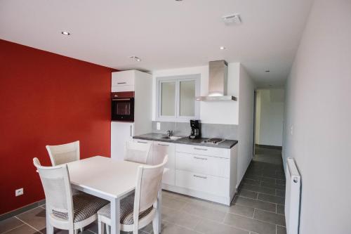 une cuisine avec une table blanche et des armoires blanches dans l'établissement Appartement Vue Mer Au Jardin De La Comtesse, à Saint-Quay-Portrieux