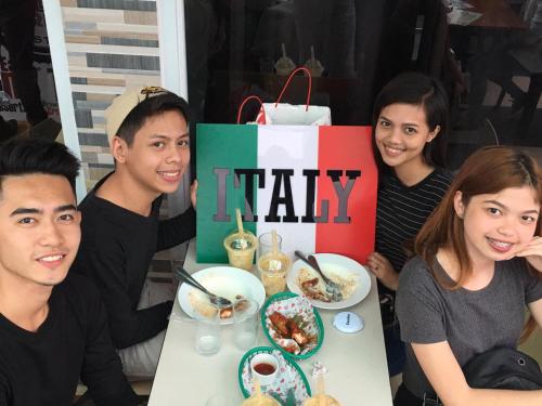 a group of people sitting around a table eating food at Italy Condotel Darasa in Tanauan