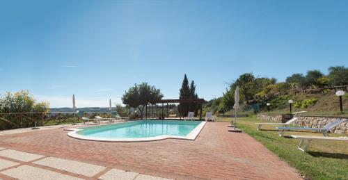 a swimming pool on a brick road with benches around it at Farm stay Il Carro del Colle in Collevalenza